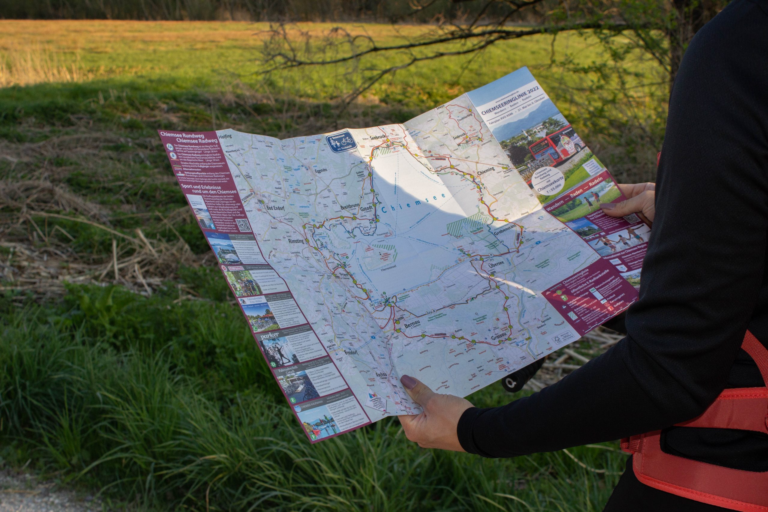 Eine Person studiert draußen in der Natur eine detaillierte Radkarte für den Chiemsee-Rundweg.