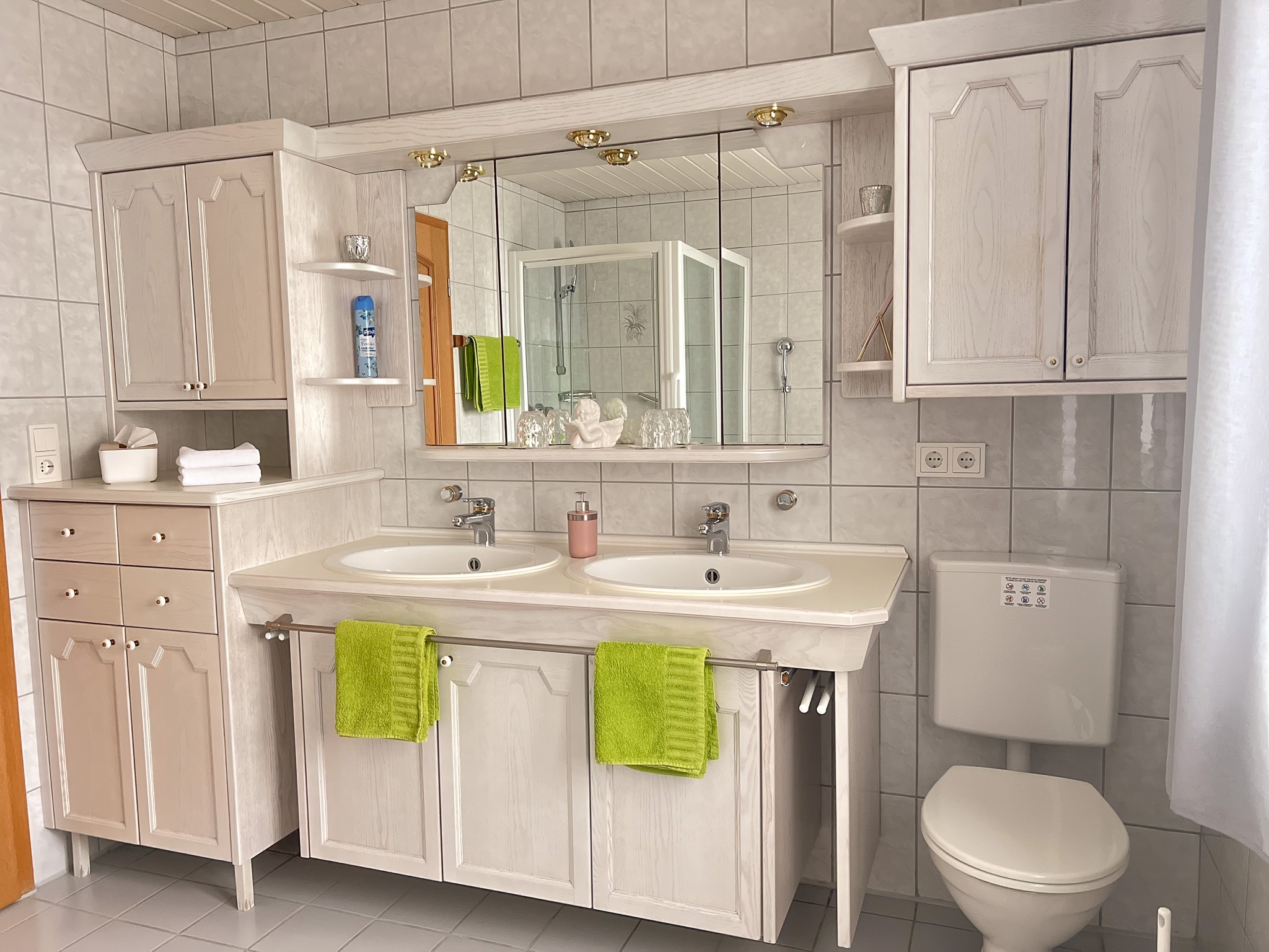 Geräumiges Badezimmer mit großem Doppelwaschbecken, Spiegeln und hellen Holzschränken.