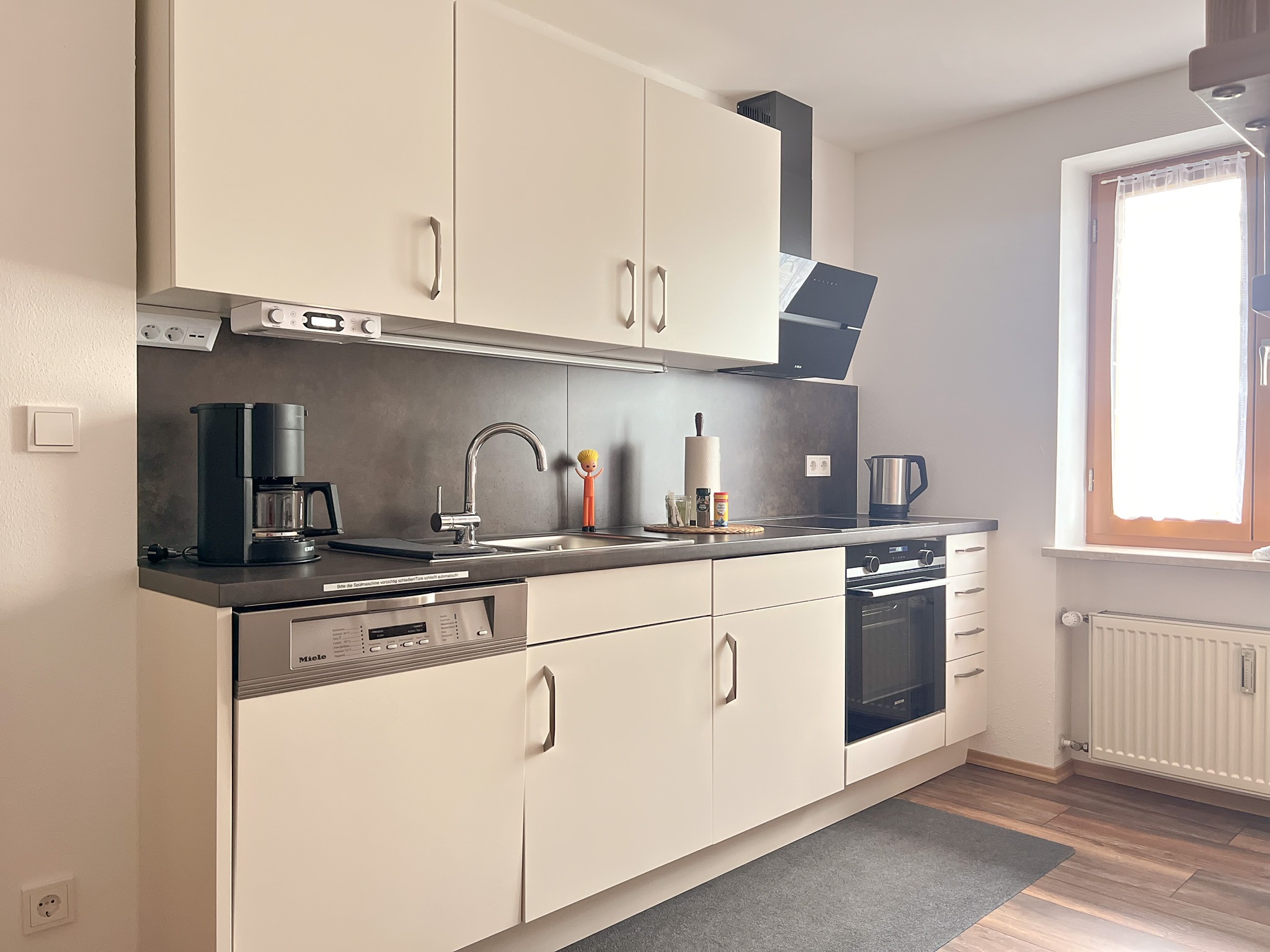 Große Ferienwohnung Bernau. Voll ausgestattete moderne Küche mit hellen Schränken und dunkler Arbeitsplatte in der Wohnung Ostflügel.